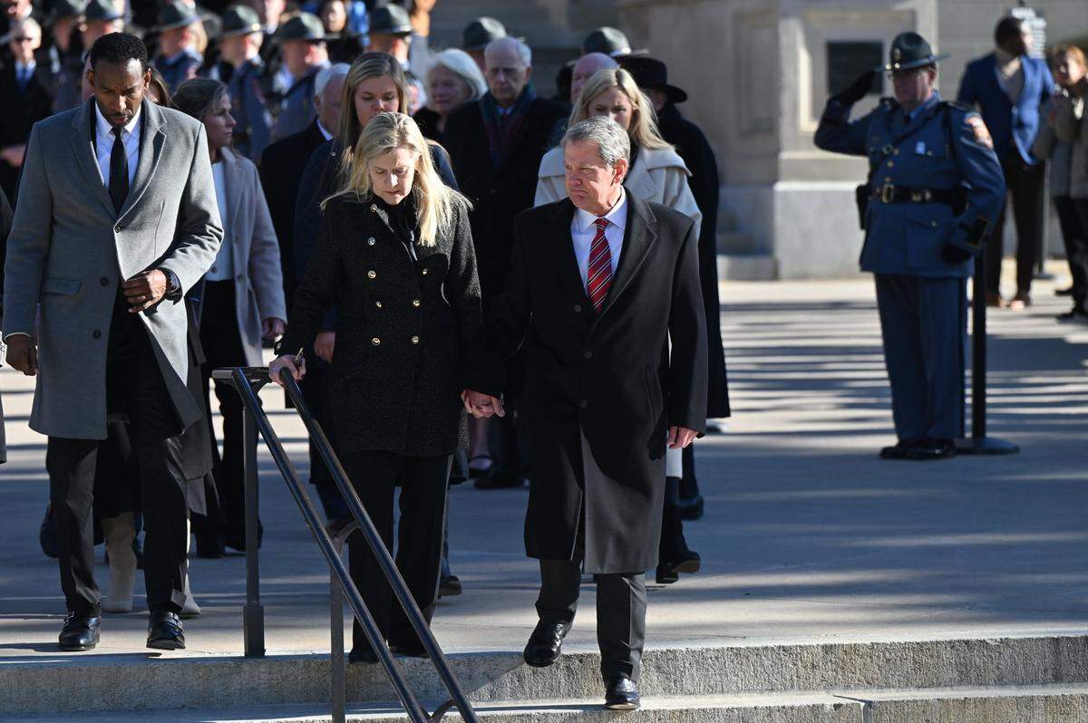Atlanta Mayor Andre Dickens (left), Georgia Gov. First Lady Marty Kemp and Georgia Governor Brian Kemp (far right) walk down the stairs as former President Jimmy Carter’s motorcade drives past the Georgia Capitol on Saturday, Jan. 4, 2025, in Atlanta, Ga.