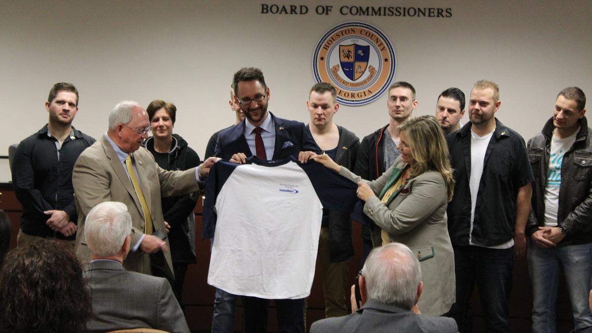 WAYNE CRENSHAW/THE TELEGRAPH 
 Houston County Commission Chairman Tommy Stalnaker, left,and Development Authority Director Angie Gheesling give a baseball shirt to Tobias Baumgartel, president of the new Sandler AG plant in Perry, as Baumgartel's team from Germany looks on.