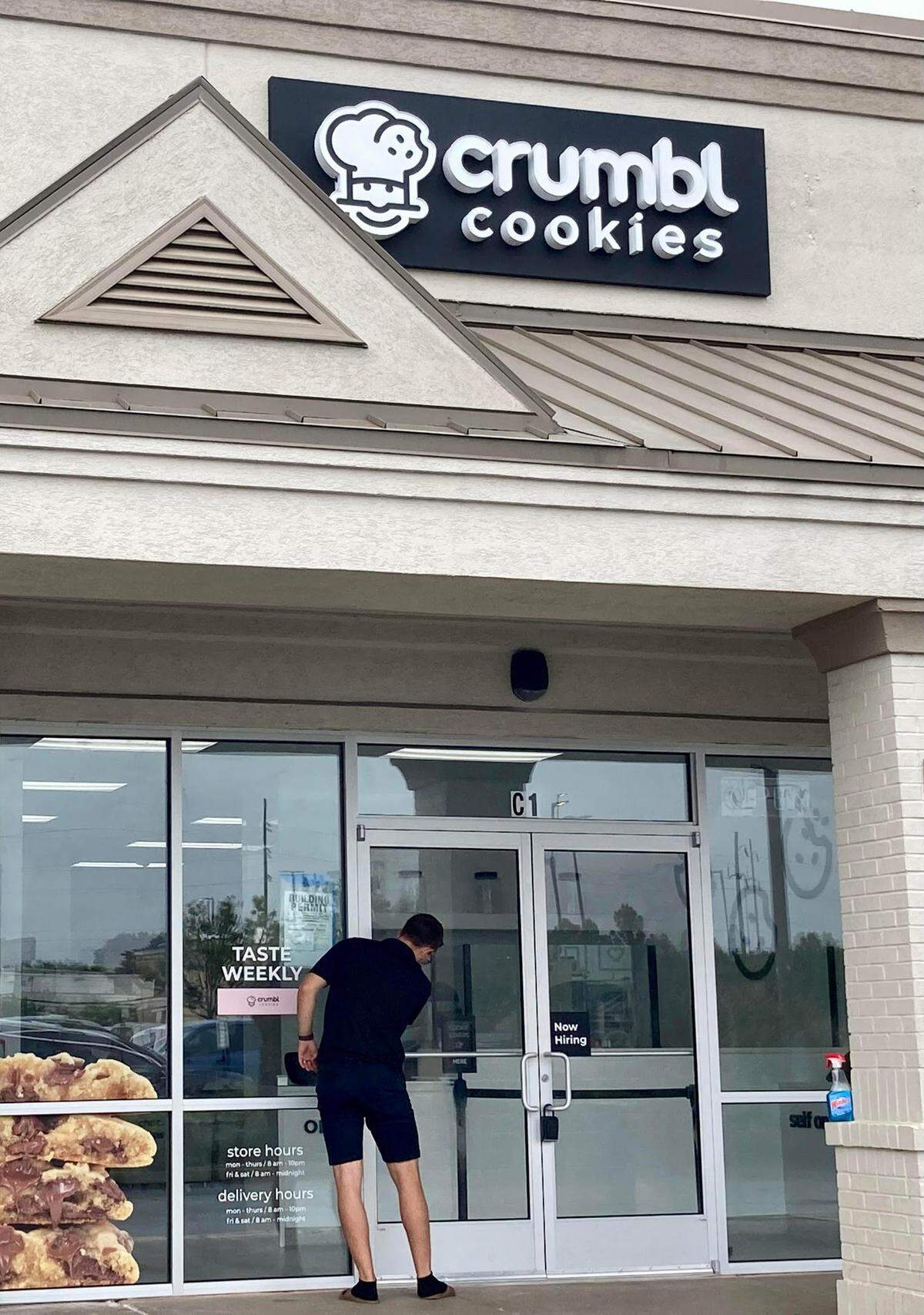 Chase Murphy, own of the franchise owners of the Crumbl Cookies store opening soon in Warner Robins, cleans the store windows.