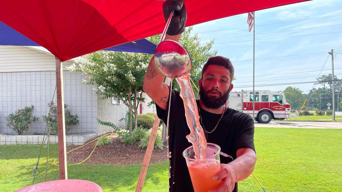 Jesus Villalon, owner of Aguas Frescas Los Cholos, fills a cup of pineapple, strawberry and kiwi agua fresca at the stand at Dunbar and Sandy Run roads in Warner Robins.