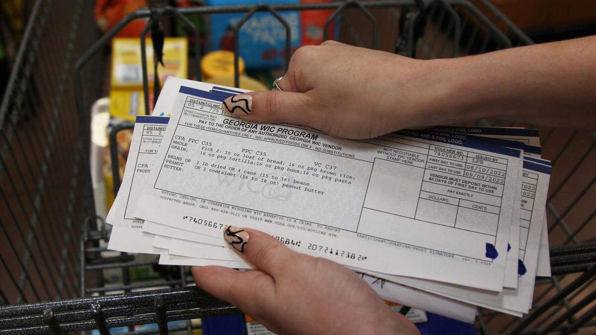 Julia Adele Callahan gets ready to sort through her paper WIC vouchers at the checkout line at a grocery store in Macon. A 2021 nationwide study in the Journal of the American Medical Association saw WIC participation increase 8% over three years in places that implemented electronic benefits.