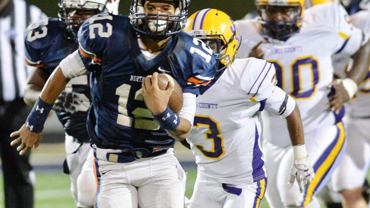 Northside quarterback Tobias Oliver (12) runs for an Eagle first down before being shoved out of bounds. The personal foul and holding against the Hounds put the ball on the 10-yard line.
