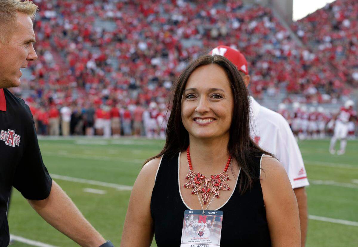 FILE - In this Sept. 2, 2017, file photo, Wendy Anderson, center, wife of Arkansas State head coach Blake Anderson, obscured at left, smiles after chatting with Nebraska head coach Mike Riley, rear, before an NCAA college football game in Lincoln, Neb. Wendy Anderson has died after a two-year fight with breast cancer. Blake Anderson says his wife died Monday night, Aug. 19, 2019, just hours after the school announced he would be taking a leave of absence. He said on Twitter: “She passed as peacefully & gracefully as you could ever hope.”