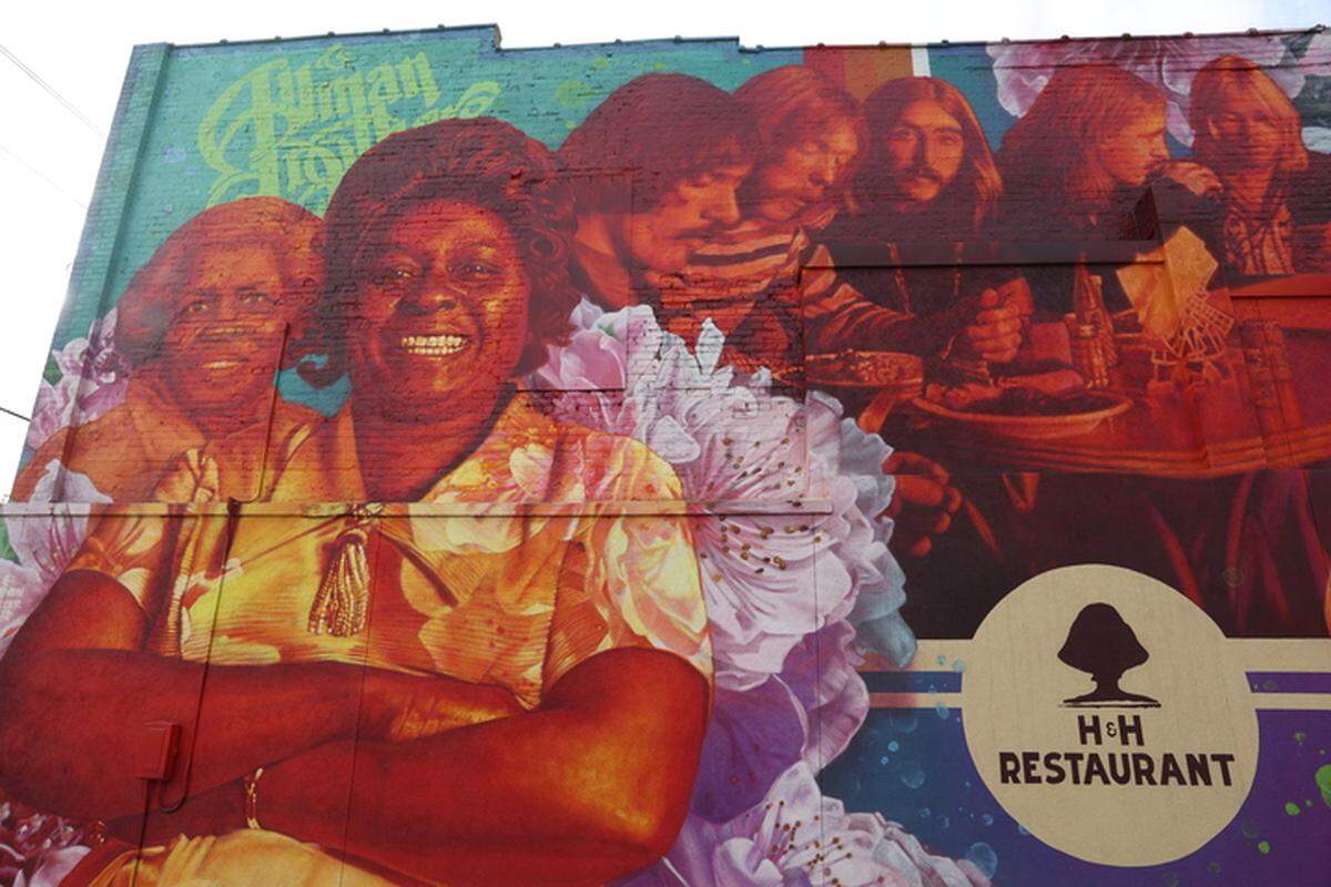 A mural off the side of H&H Restaurant, depicting founders Inez Hill and Louis Hudson with members of The Allman Brothers Band eating their soul food. The band sparked a relationship with the two owners. 