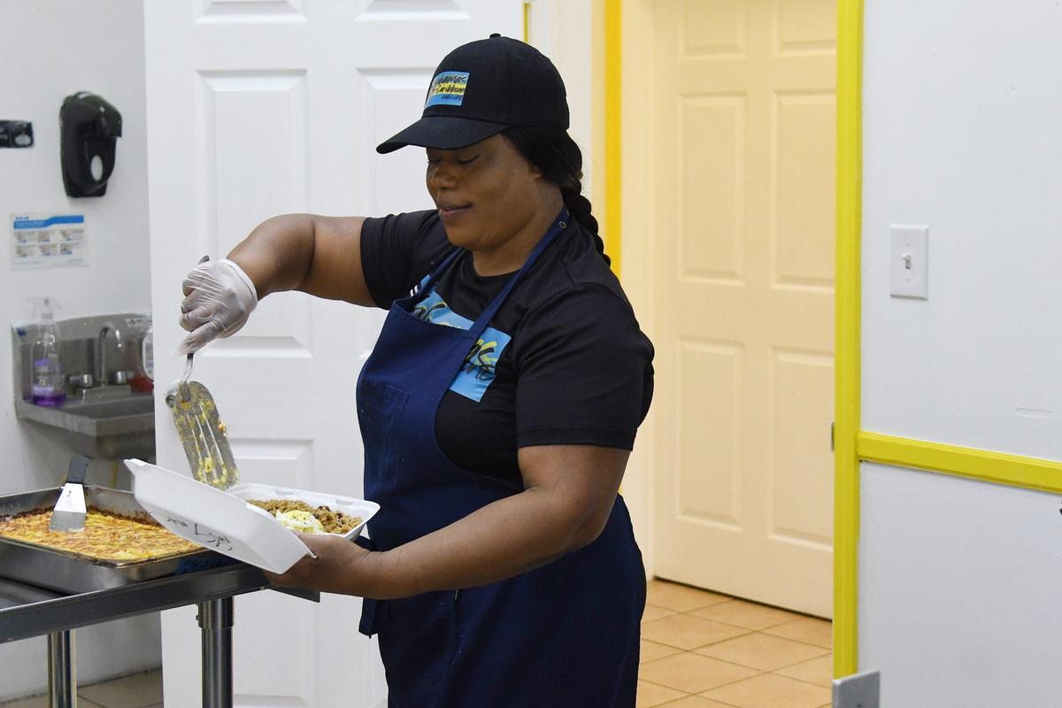 Co-owner Shantel Major scoops baked macaroni and cheese made from scratch into a to-go box at Bahamas Caribbean Cuisine on Thursday, Aug. 15, 2024, in Warner Robins, Georgia. The new restaurant serves authentic Bahamian food.