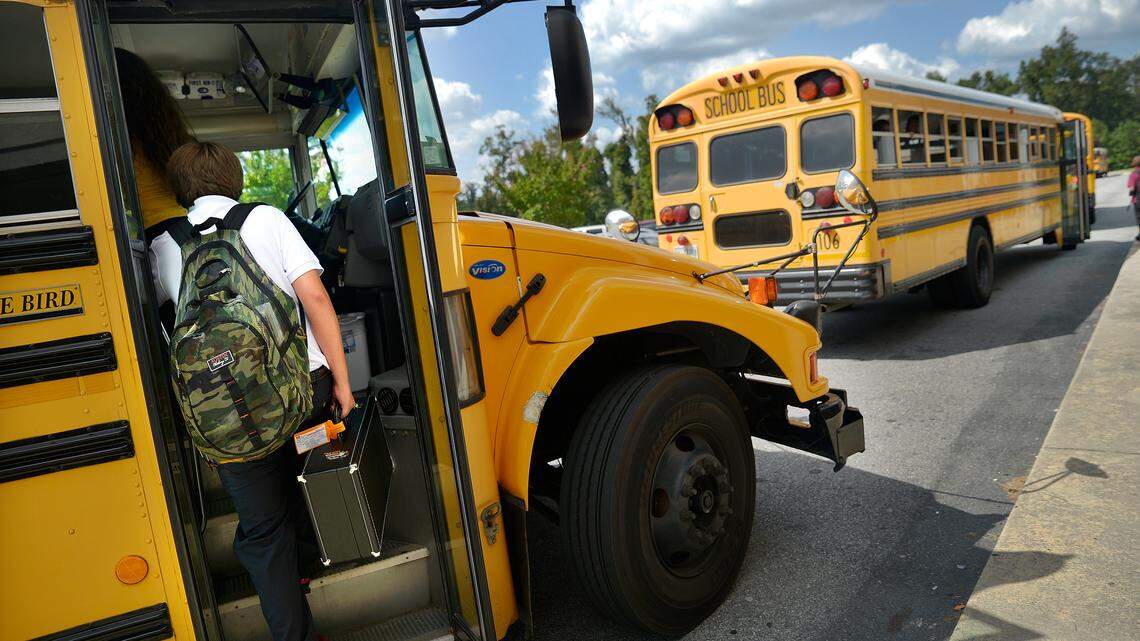 A Weaver Middle School student boards his bus with a backpack and instrument case.