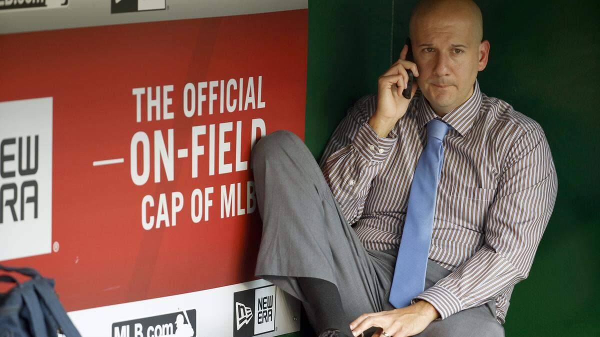 Atlanta Braves assistant general manager and director of pro scouting John Coppolella talks on the phone in the dugout during batting practice before a baseball game against the Washington Nationals at Nationals Park, Friday, Sept. 4, 2015, in Washington. (AP Photo/Alex Brandon)