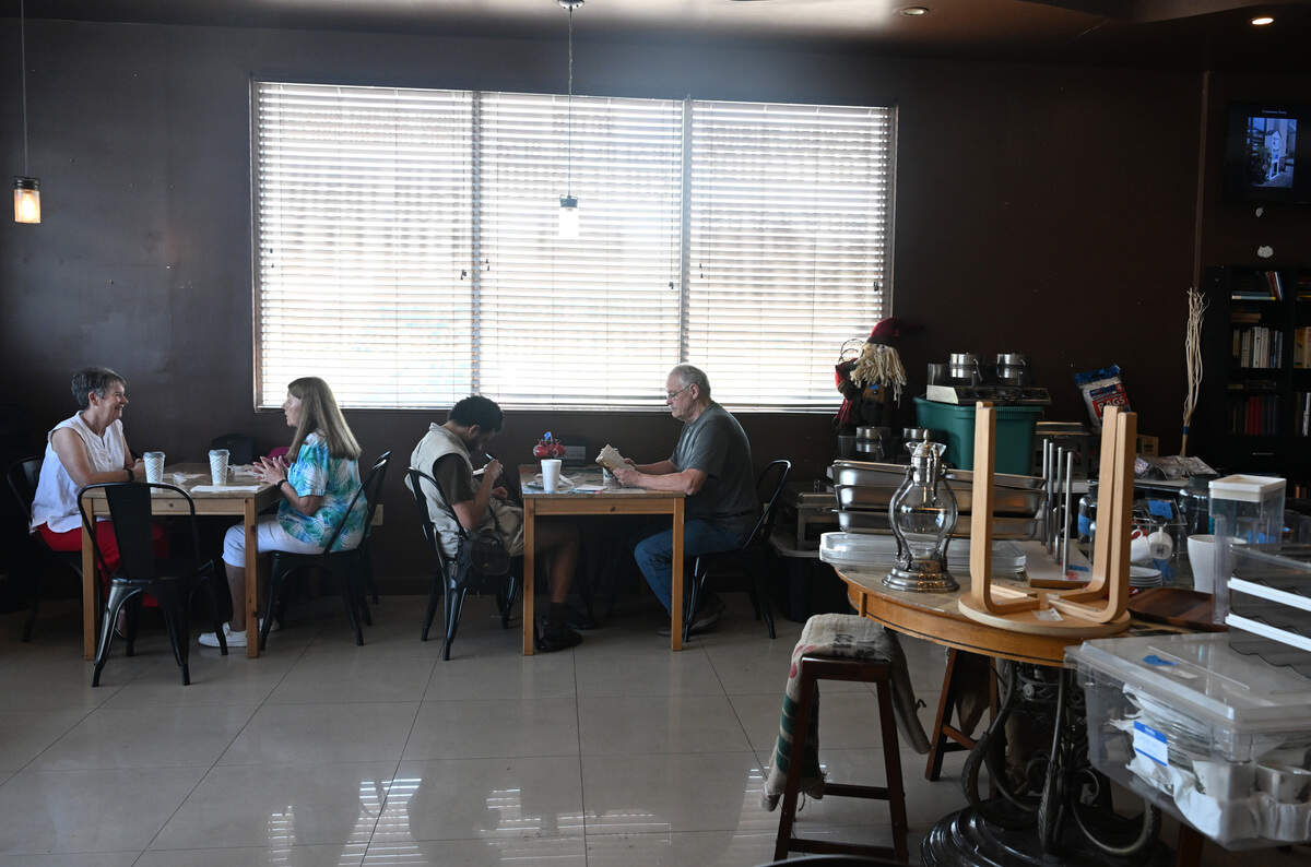 Customers, including Kyle Crawford and his grandson, Nicholaus Kyle Crawford, sit inside Between Friends Coffee on Wednesday, June 10, 2026, with items are set out for the coffee shop’s liquidation sale on Monday, June 15, 2026.
