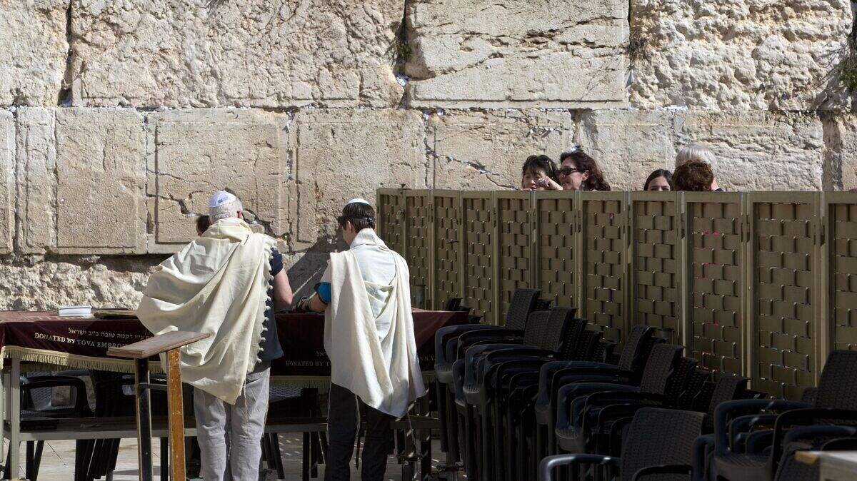 A Jewish man and youth pray as women looks at the Western Wall, the holiest site where Jews can pray in Jerusalem's Old City on Monday.