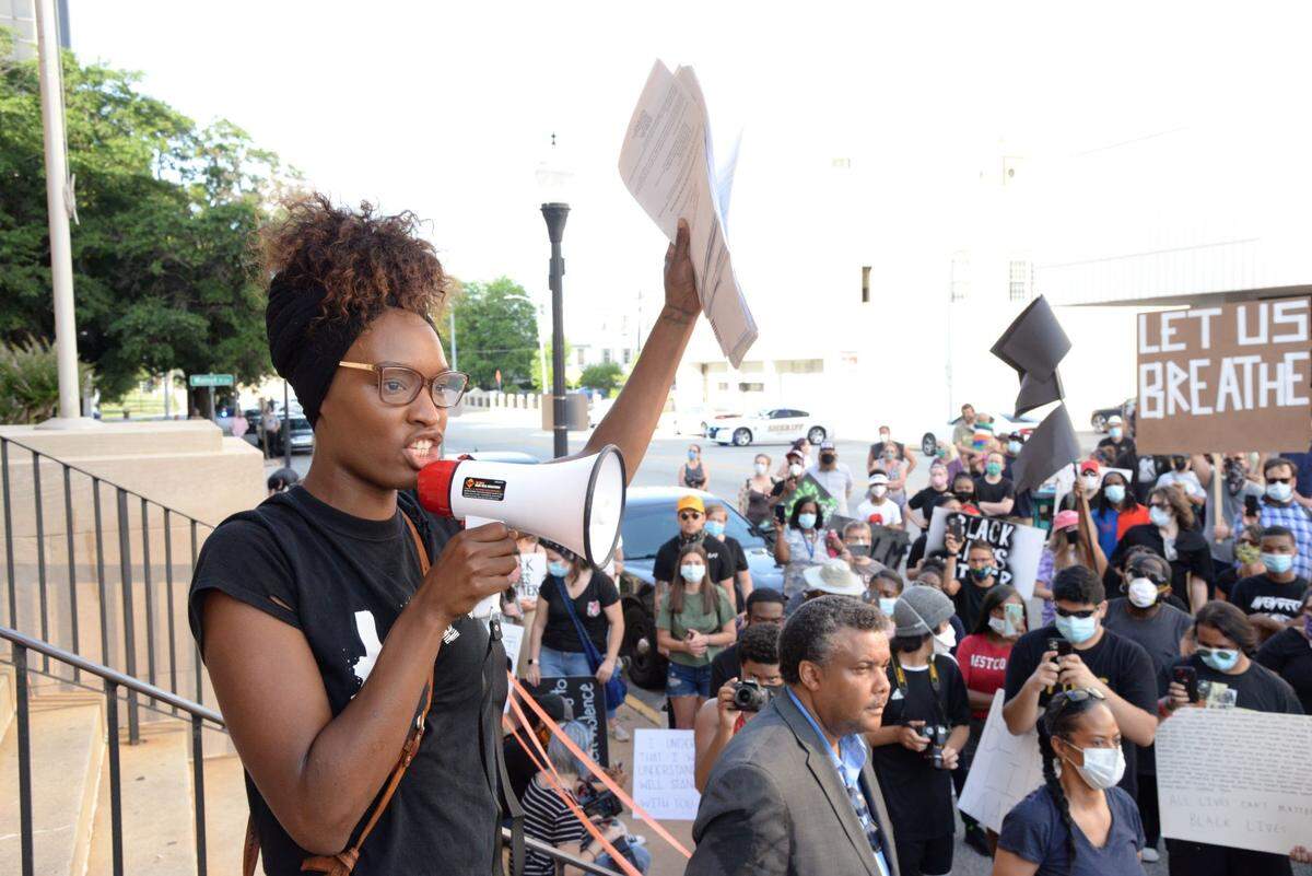 Local small business owner and activist Andréa Glover encourages a crowd of marchers to register to vote and vote in the June 9 election. The march began in front of the Tubman Museum in downtown Macon Tuesday evening and stopped in front of city hall and the county courthouse.