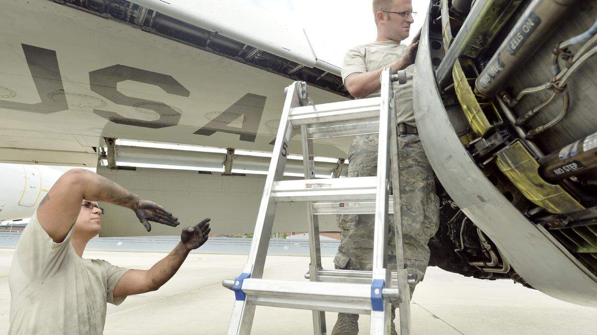 Sr. Airman Robert Shropshire, left, gives a suggestion for Staff Sgt. Jason Balser while working on a JSTARS engine in this 2014 file photo.  A faulty engine scattered debris last week, damaging four planes.