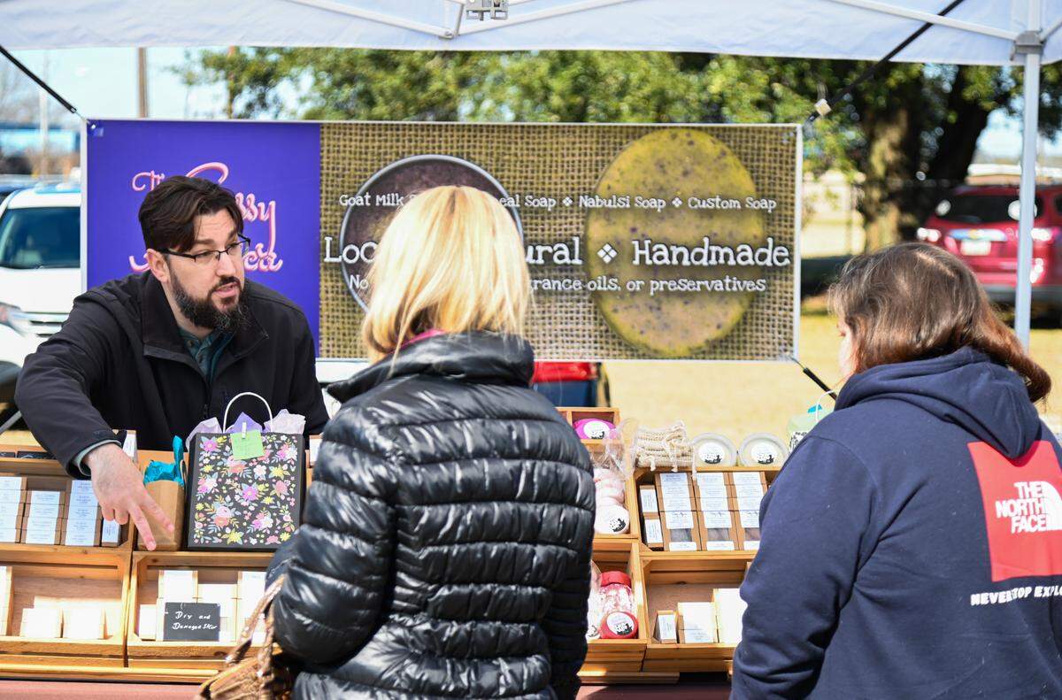 Joshua Hess, owner of The Sassy Alpaca, helps customers Thursday at his booth at the International City Farmer’s Market in Warner Robins. He’s opening a storefront soon in Ingleside Village in Macon.