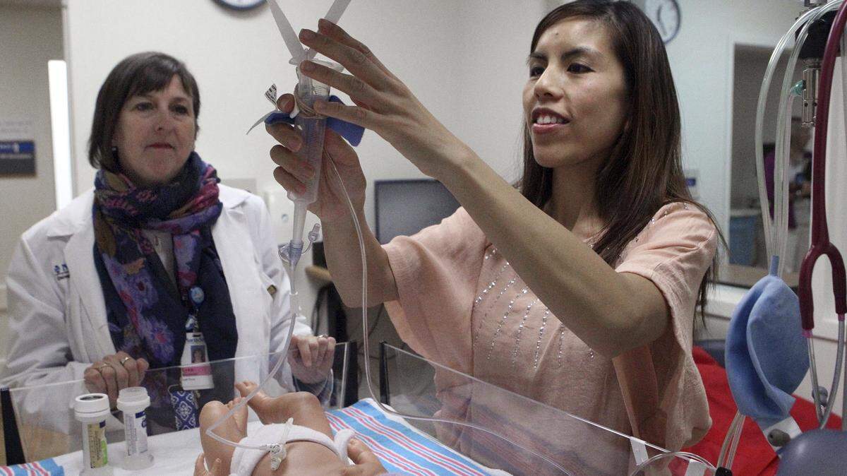 Kevin Tanaka/Lake County News-SunJenny Vergara learns to care for her daughter’s medical needs on a “sim-baby” as Lynn Mayberry, left, observes in the Infant Special Care Unit at Evanston Hospital in Illinois.