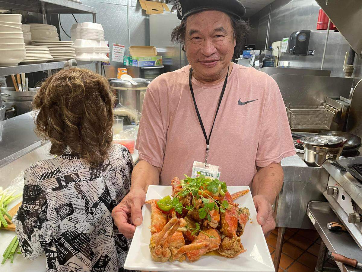 Quang Pham, who owns Saigon Bowl, a new authentic Vietnamese bistro in Warner Robins, with his wife, Thao Le, carries a lobster dish called “Tom Hum Rang Muoi” he’s just prepared on Wednesday, June 18, 2025. Le, with back turned, is slicing vegetables.