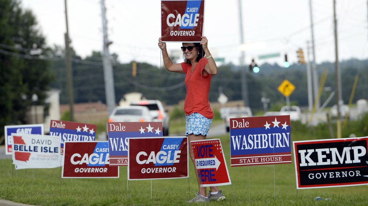 Gaylyn Cole, holding a sign for her favorite runoff contender, said she would likely be out until the close of the polling place at Mabel White Baptist Church Tuesday.  "Don't mind the rain and don't mind the heat," she said.  "Well, if it's not raining too hard."