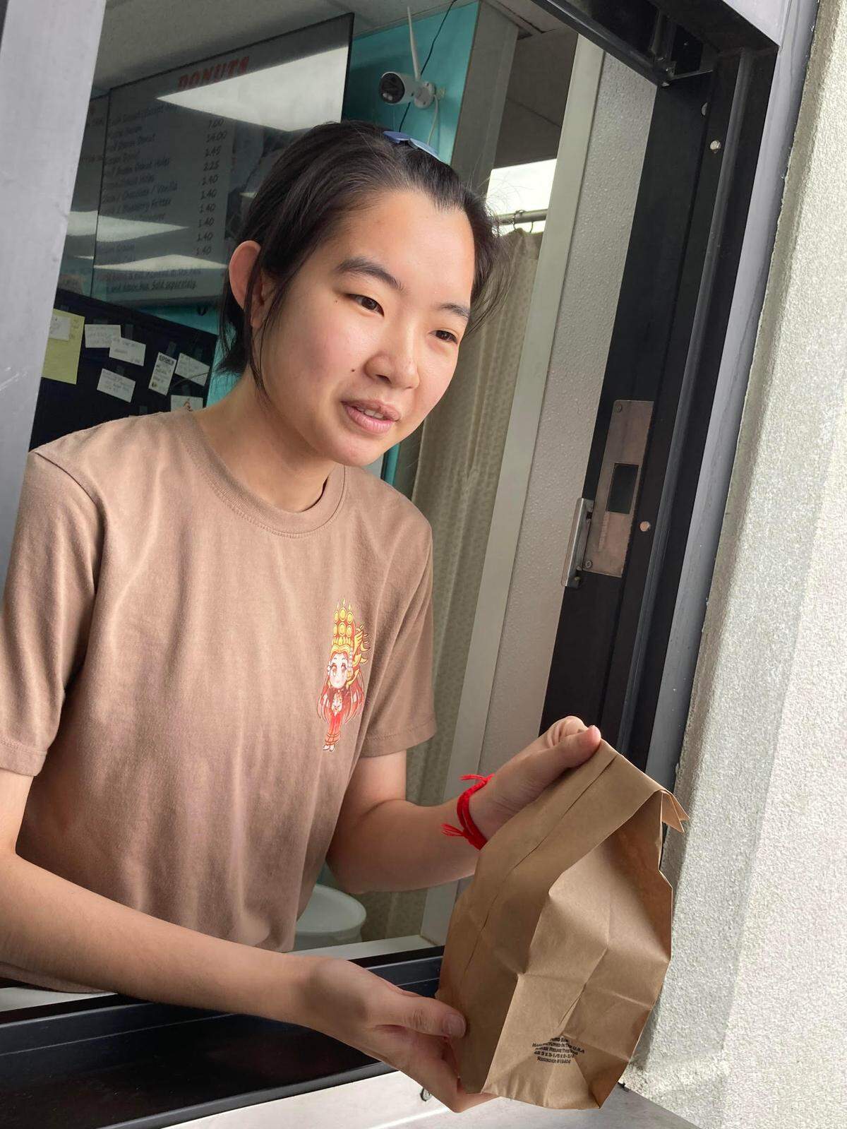 Kimhang Eang, a Cambodian native, hands an order out to a waiting motorist in the drive thru lane at Ray’s Donuts in Warner Robins.