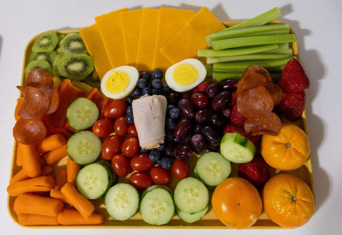 A kids-cuterie board prepared by local chef, Tyler Taliaferro. In the board there are fresh fruits and vegetables, meats, and cheeses organized in a smiley face.