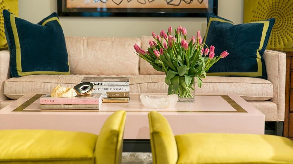 Tobi Fairley’s Ellison cocktail table for Woodbridge features a blush top with gold leaf border on a frame and legs finished in a shade of charcoal. She teams it with a matching linen sofa, navy pillows with citron yellow borders and citron stools.
