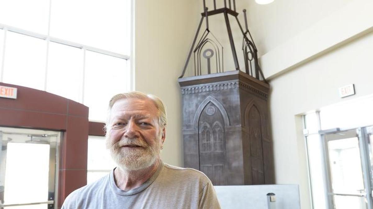 Sculptor Jim Bodell stands in the lobby of a Mercer University Medical School building, in what used to be the Georgia Music Hall of Fame, where his abstract depiction of the university’s administration building is now on display.