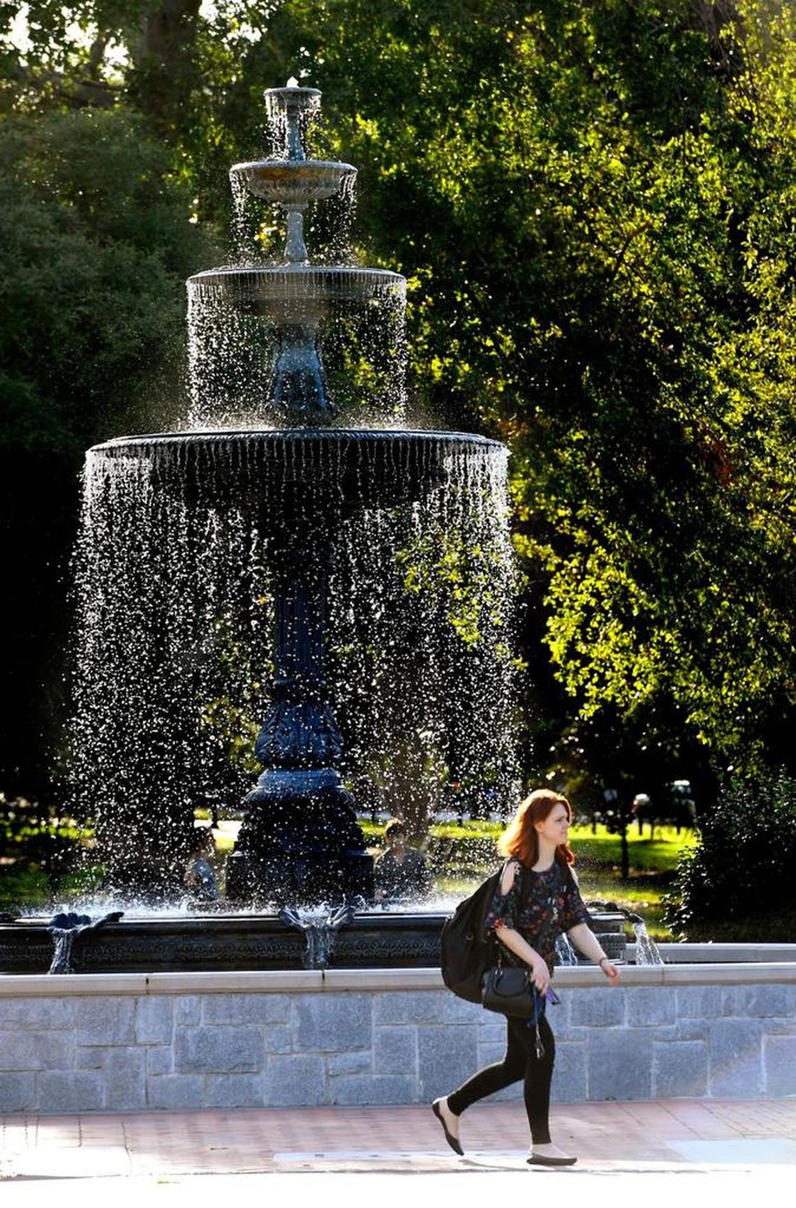 Emily Herron, a Mercer student walks by the fountain in Tattnall Square Park on Monday after a day of studies. Of the weather Herron said, "It's finally starting to feel like fall."