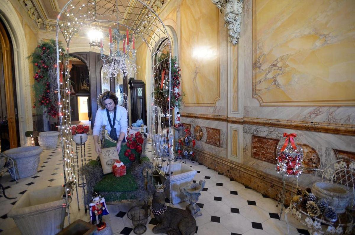 Suzanne Rogers adds moss to Santa's chair in grand hall.