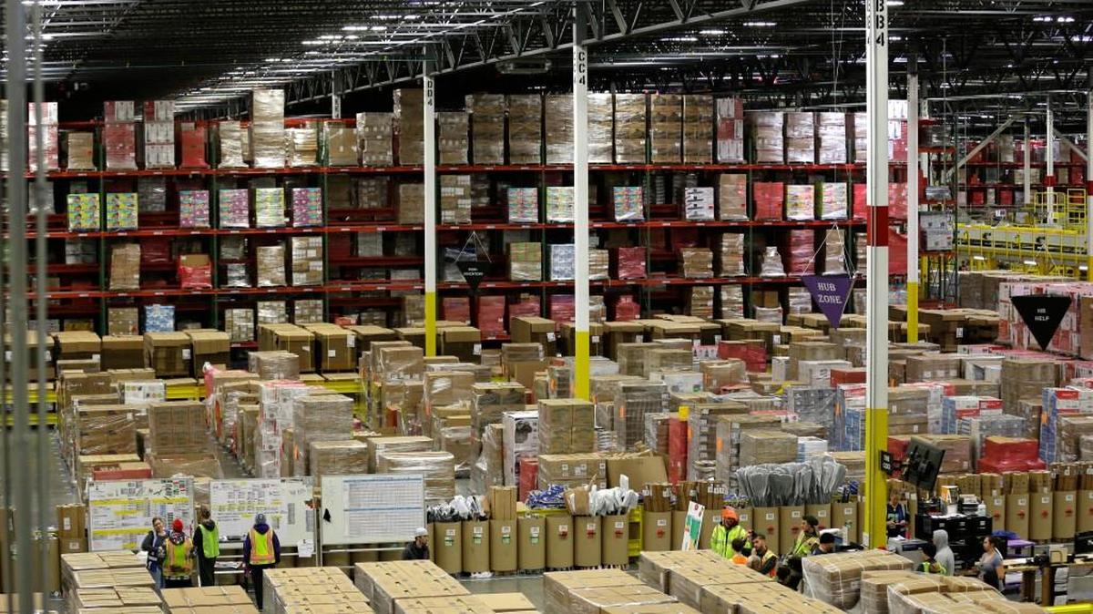 Workers gather in a section packed high with merchandise at Amazon.com's fulfillment center in DuPont, Wash.
