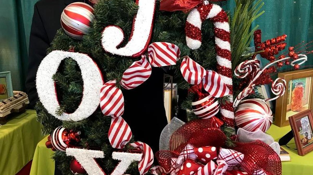 Mark Ballard holding the wreath of joy he created. Members of the audience saw it differently, depending on the placement of the letters, and their perspective.