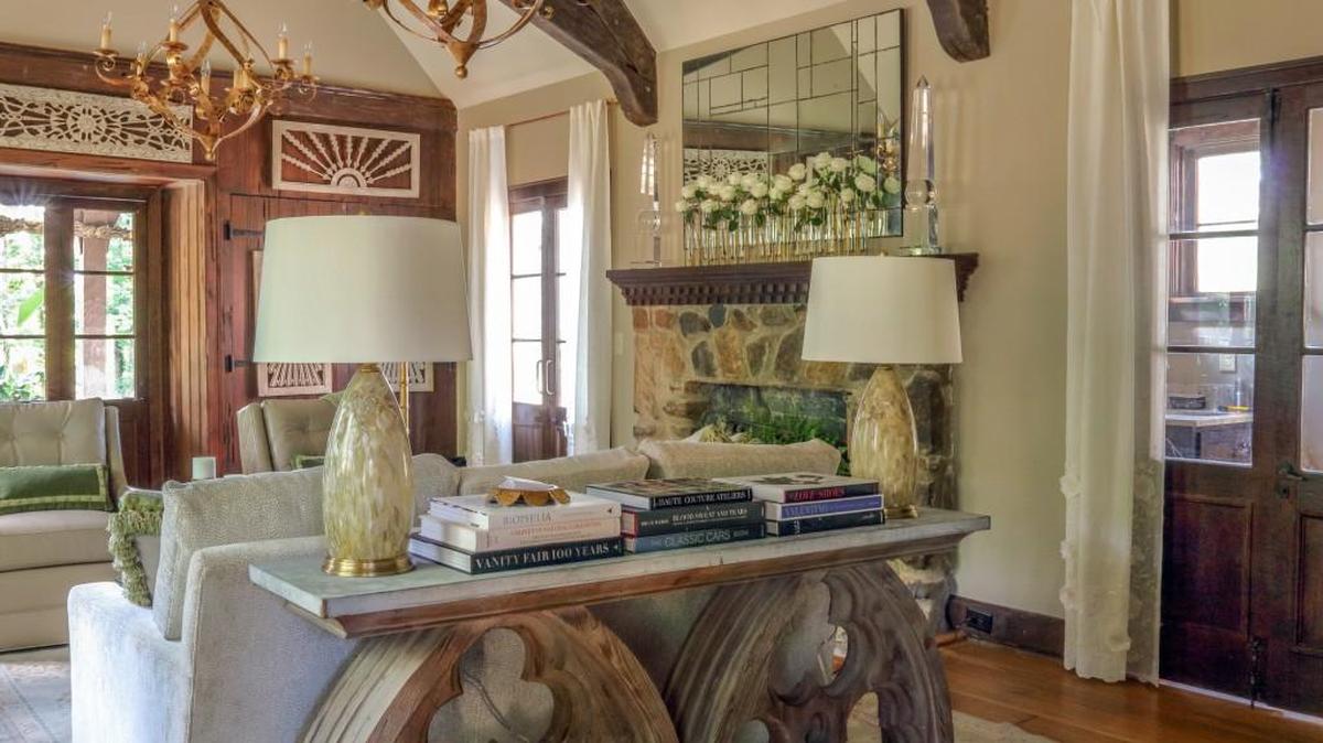 At the Design House, Sally Draughon, owner of Preview Interiors, updated the main living area with a sophisticated monochromatic color palette. Two large swirls of burnished gold provided subdued lighting from the beamed ceiling.