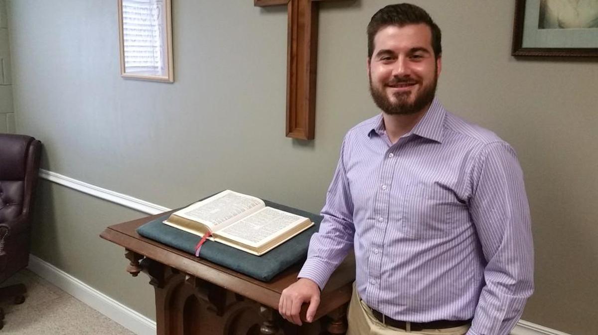 The Rev. Greg Harrison by a hand-carved pulpit from the days when Wesley United Methodist Church was known as Jones Chapel, from 1887 to 1904.