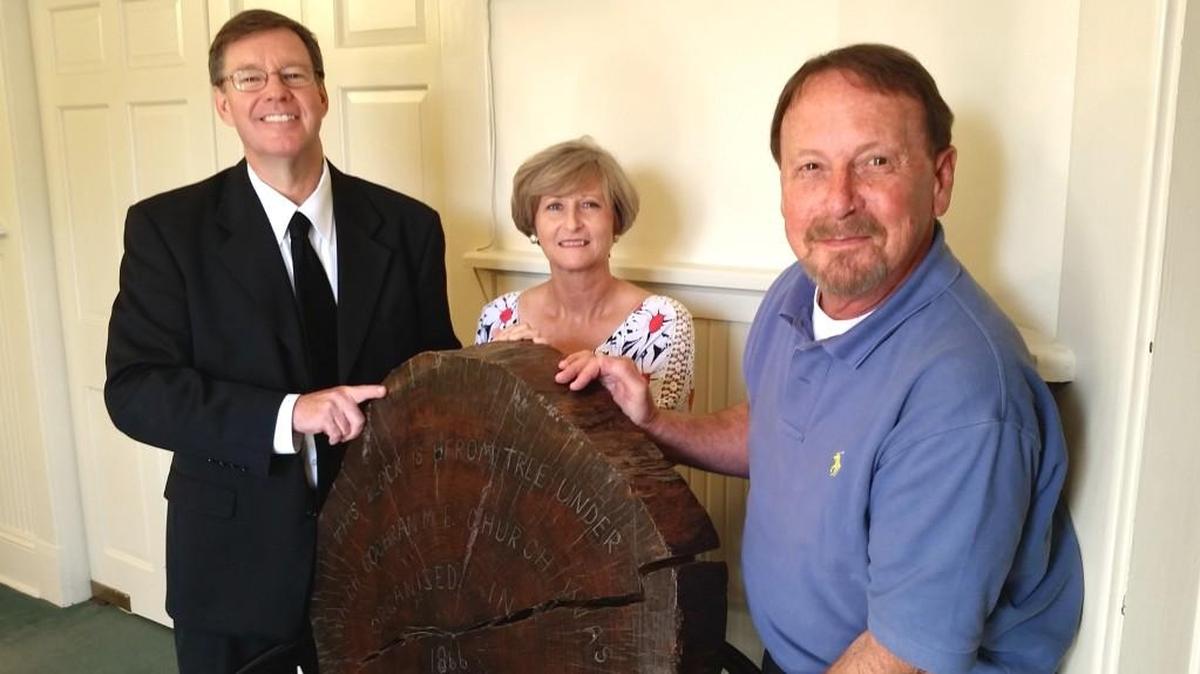 The Rev. Bill Woodson, Jim Rambo and Judy Farrell with a slice from the trunk of the great tree original members of the congregation of First United Methodist Church of Cochran worshipped under 150 years ago.