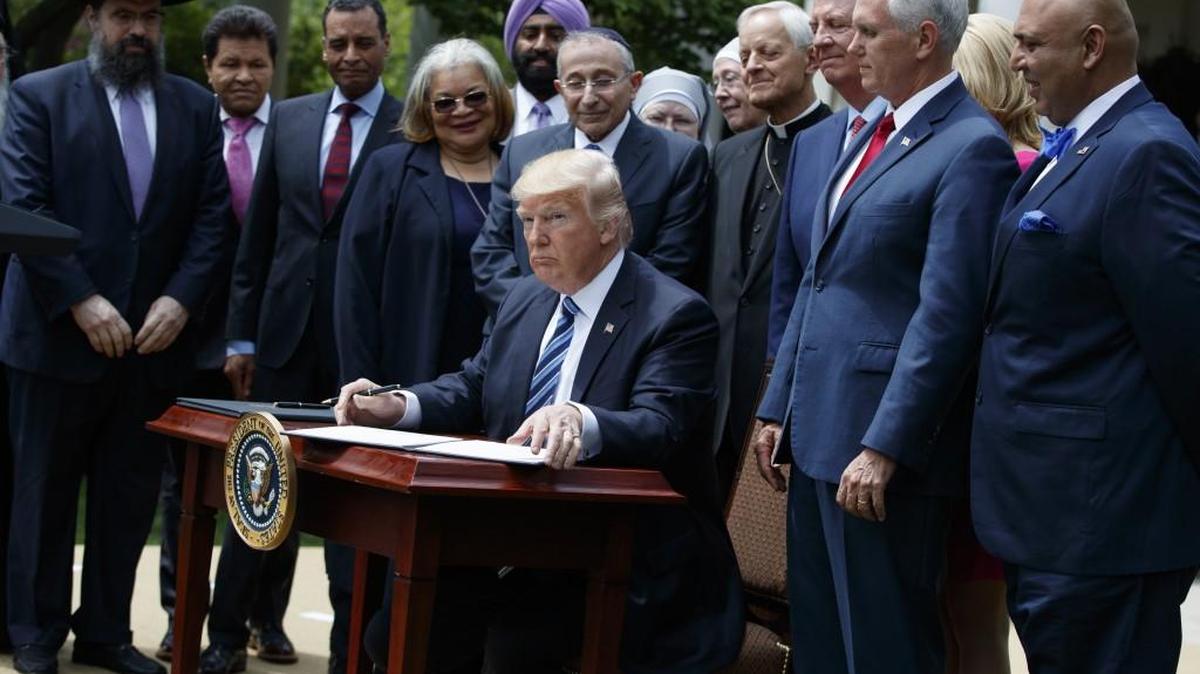 President Donald Trump signs an executive order aimed at easing an IRS rule limiting political activity for churches on May 4 in the Rose Garden of the White House in Washington.