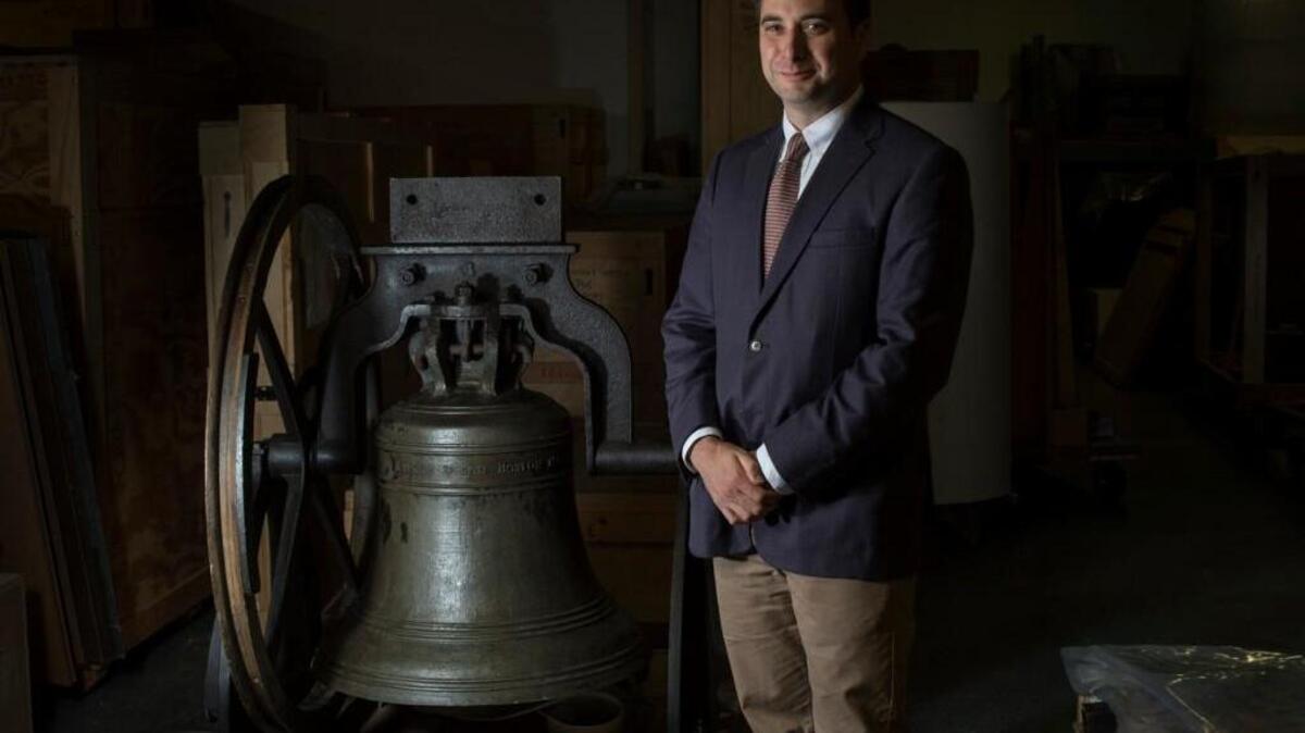Peter Manseau stands next to a church bell made by Paul Revere at the Smithsonian National Museum of American History in Washington.