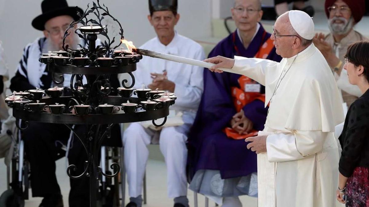 Pope Francis lights a candle Tuesday during the closing of an inter-religious prayer gathering in front of the Basilica of St. Francis in Assisi, Italy.
