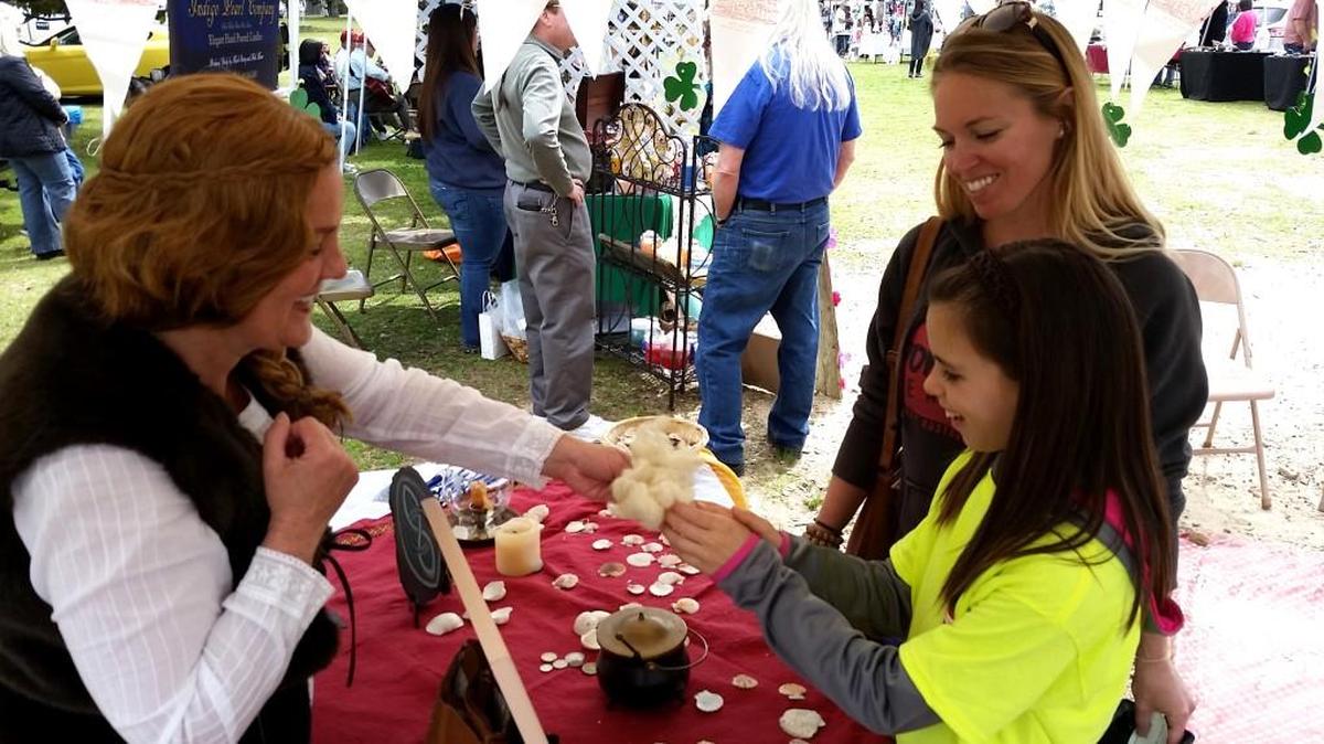 Amy Elton, left, shows Rhianna Pickard and her daughter Cami Pickard, of Newnan, wool from Ireland at Wesleyan Market. Elton was dressed as an Irish peasant who told stories of the Emerald Isle and her friendship with St. Patrick.