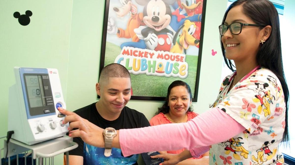 West Little Havana resident Jose Amaya, 14, gets his blood pressure measured by Gisselle Nogueira, a medical assistant at Nicklaus Children's Hospital, as his mother Sandra Amaya looks on at the hospital in Coral Terrace, Florida.