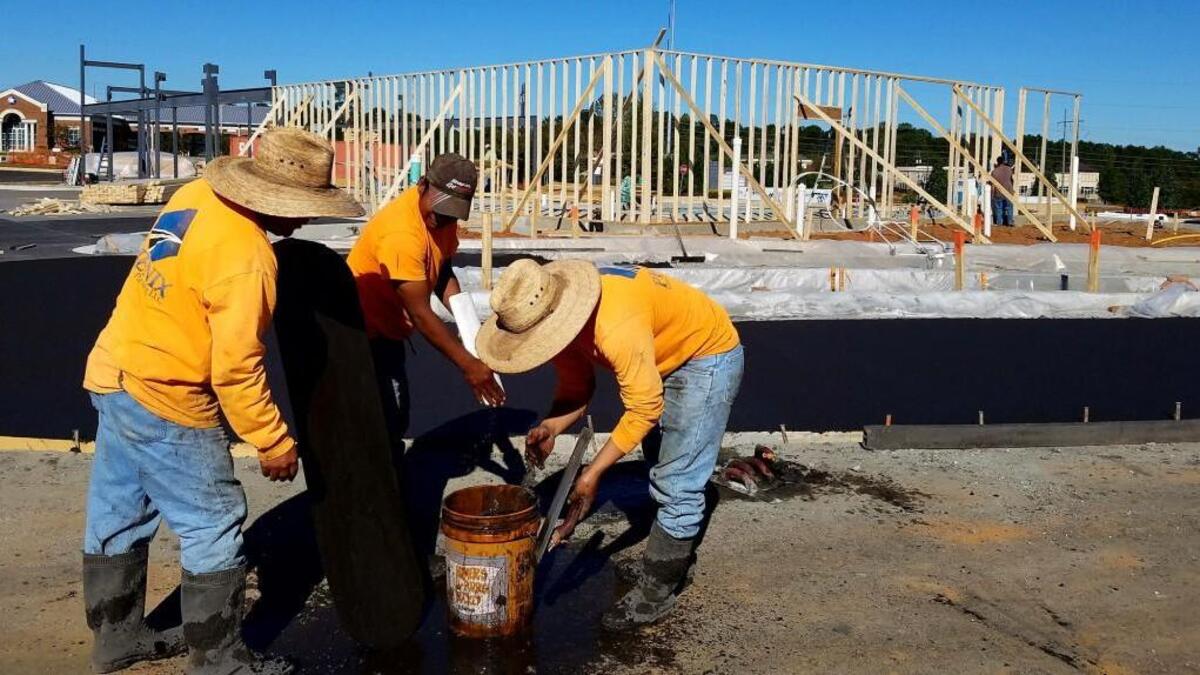 Construction workers clean up concrete finishing tools Tuesday in the drive-thru of the Burger King restaurant being built on Bowman Road in north Macon.