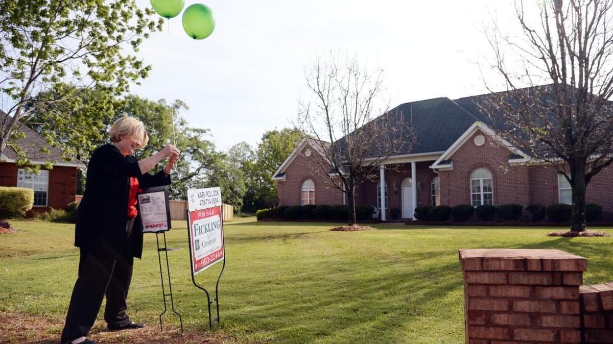 Associate broker Kari Pollock, with Fickling & Co., ties balloons to a sign prior to a open house at 102 Carrington Court in Kathleen on Saturday morning.