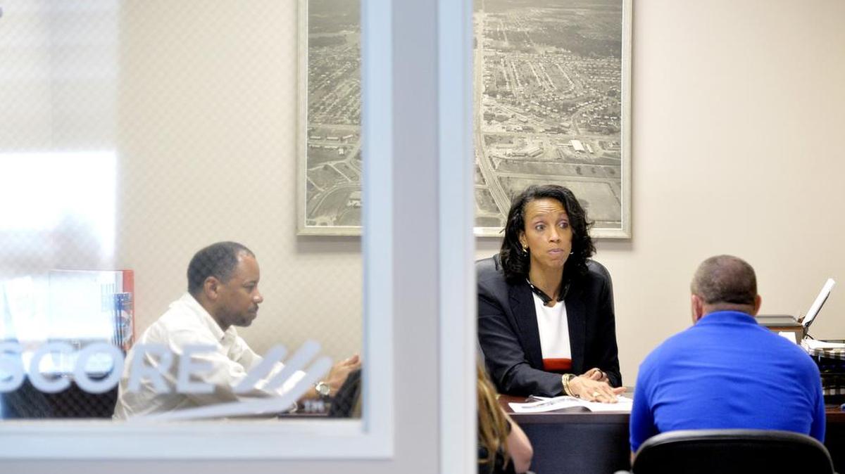 Keith King, left, and Ulrica Jones, with Score Middle Georgia, speak with Patrick and Lori Young, owners of Centerville Gun and Pawn, inside the Robins Regional Chamber of Commerce on April 20.