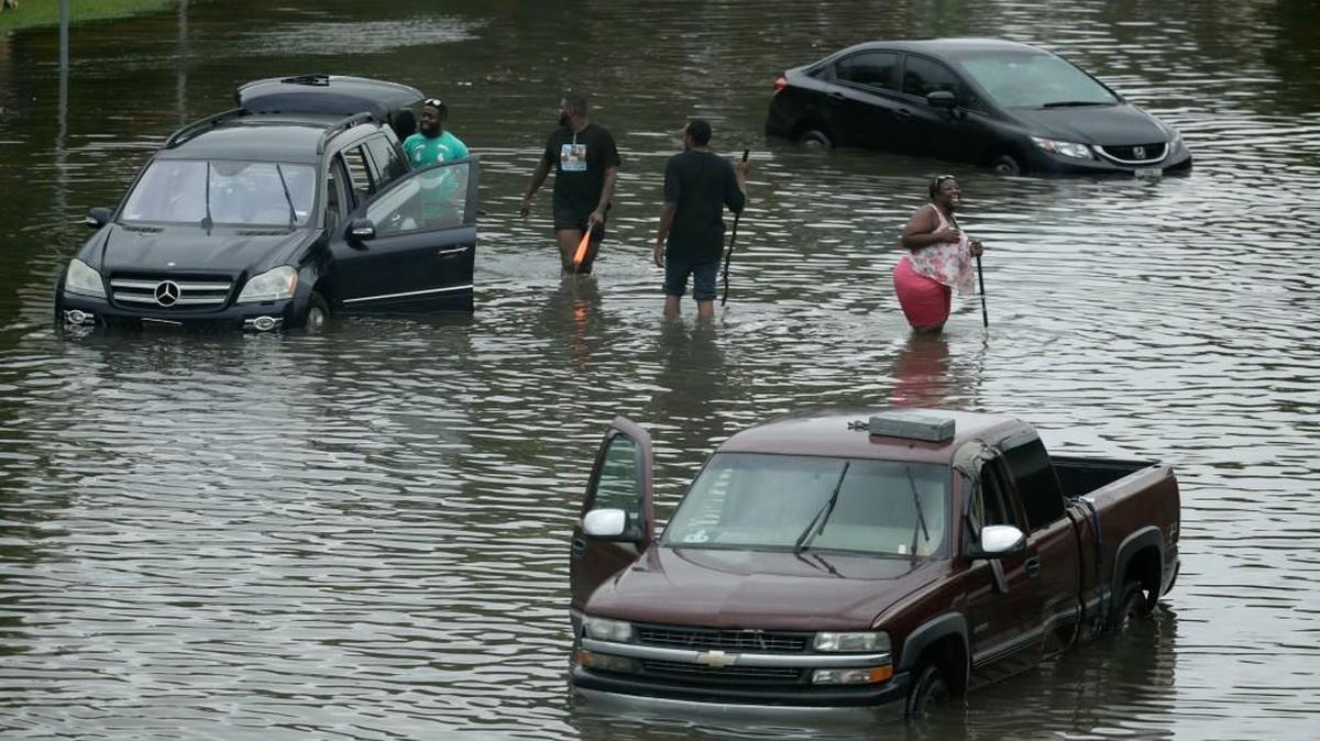 People walk among stalled cars in a neighborhood flooded by Tropical Storm Harvey on Sunday, Aug. 27, 2017, in Houston, Texas.