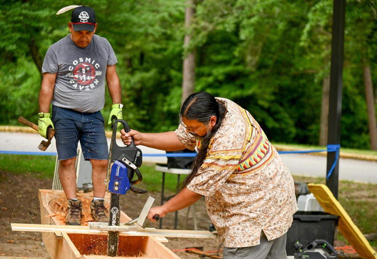 Pedro Zepeda, right, with the Seminole Tribe of Florida and John John Brown with the Muscogee Nation work on completing a 13-foot dugout canoe Wednesday outside the visitors center at Ocmulgee Mounds National Historical Park.