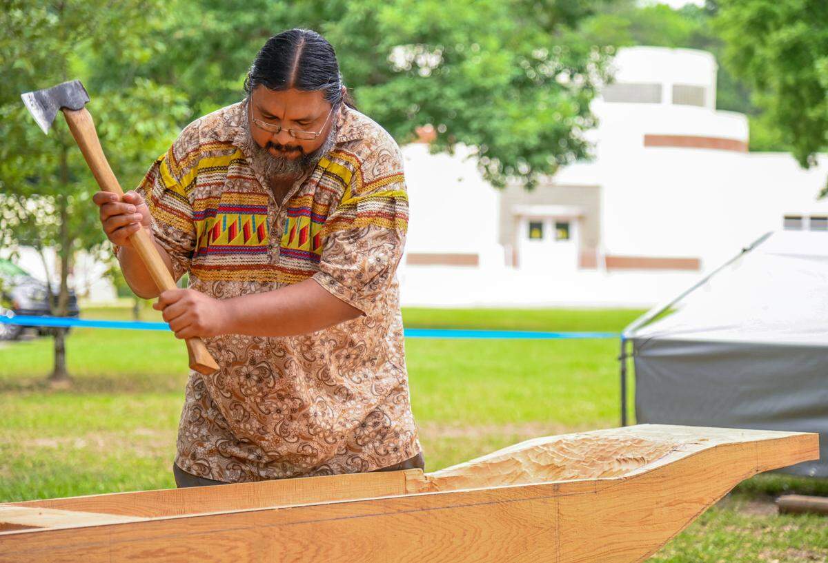 Pedro Zepeda with the Seminole Tribe of Florida uses an axe while helping complete a 13-foot dugout canoe Wednesday outside the visitors center at Ocmulgee Mounds National Historical Park.