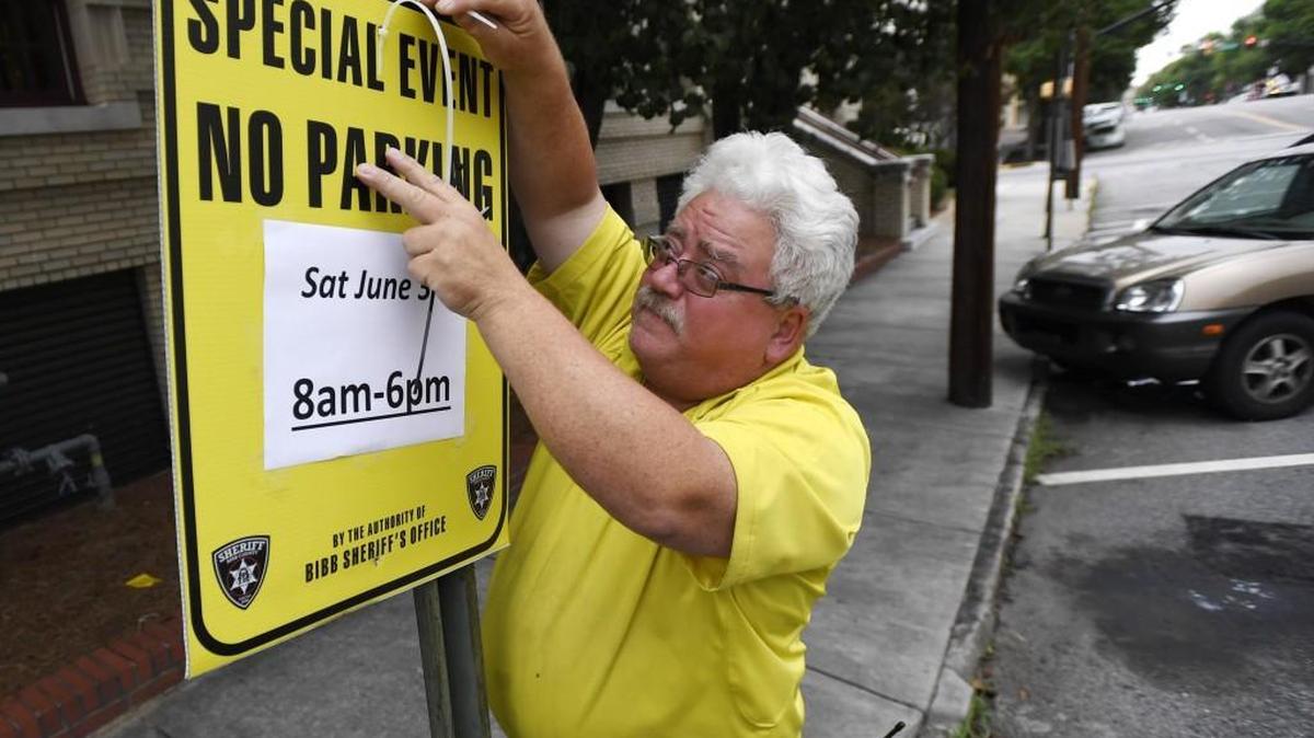 Stanley Hunnicutt with parking enforcement puts up a sign letting people know that Cherry Street will be closed to parking Saturday 8 A.M. to 6 P.M.