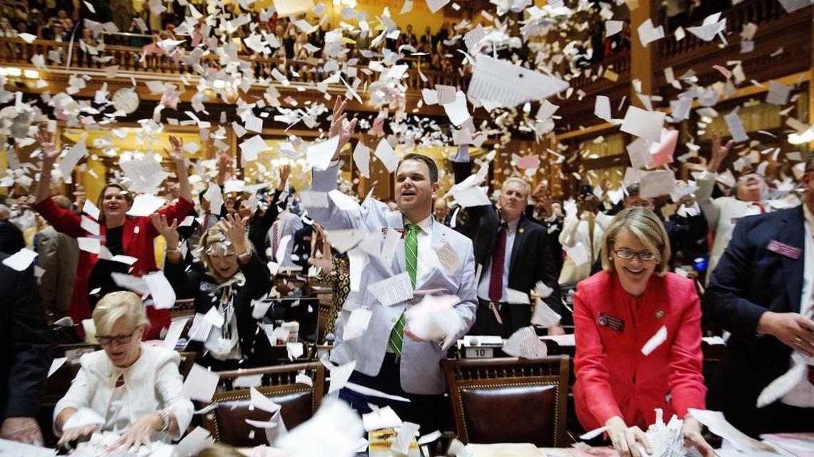 State Rep. Christian Coomer, R-Cartersville, center, and fellow lawmakers throw up paper from their desks at the conclusion of the legislative session in the House chamber, in Atlanta, Friday, March 31, 2017.
