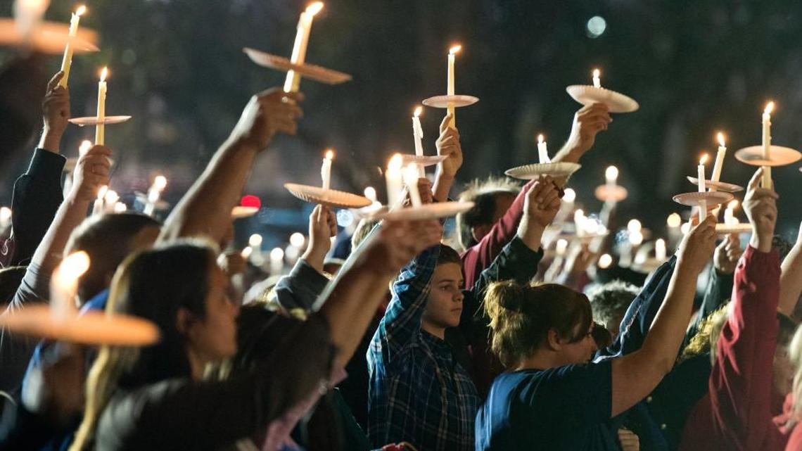 Mourners hold lit candles in the air during a vigil for Peach County Sgt. Patrick Sondron and deputy Daryl Smallwood at North Peach Park in Byron Tuesday night.