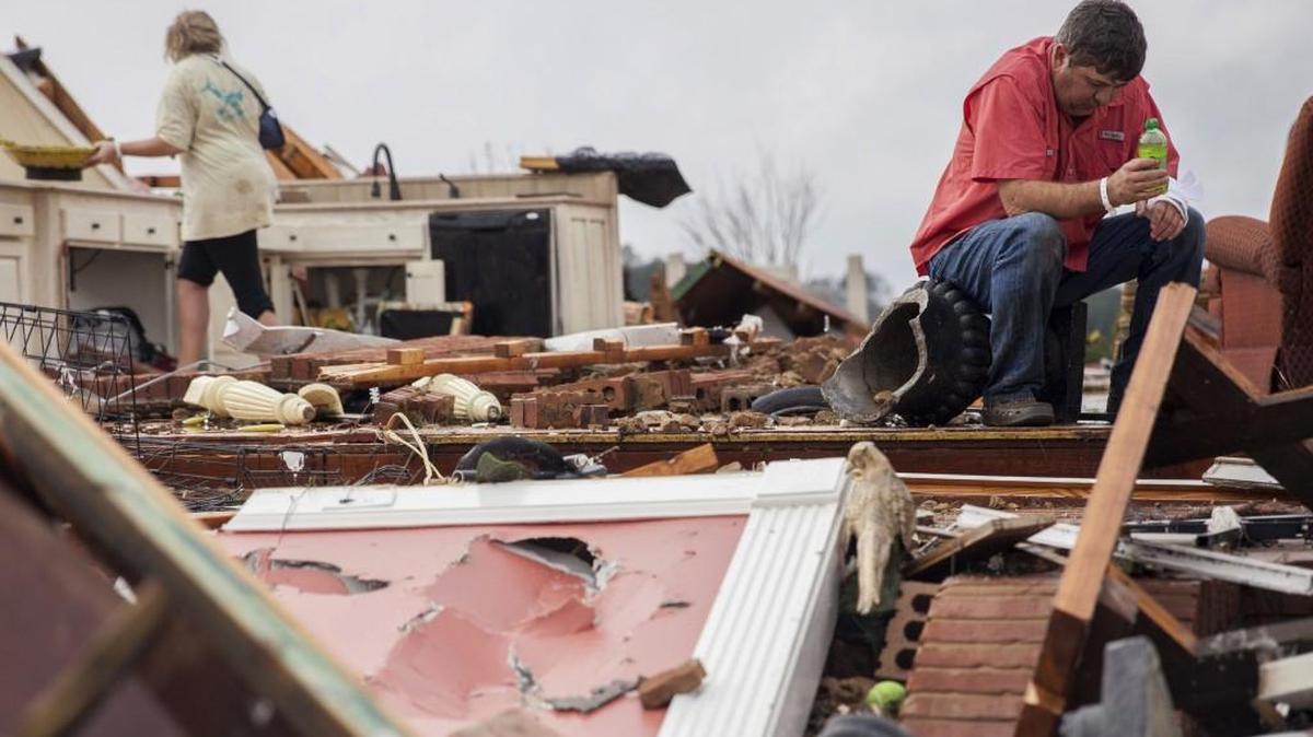 Jeff Bullard sits in what used to be the foyer of his home as his daughter, Jenny Bullard, looks through debris at their home that was destroyed by a tornado last month in Adel.