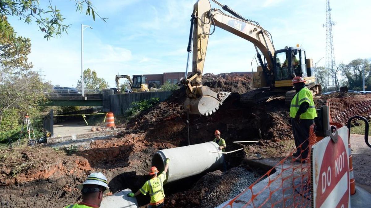 Workmen install a 3-foot pipe under a section of the Ocmulgee Heritage Trail Wednesday.