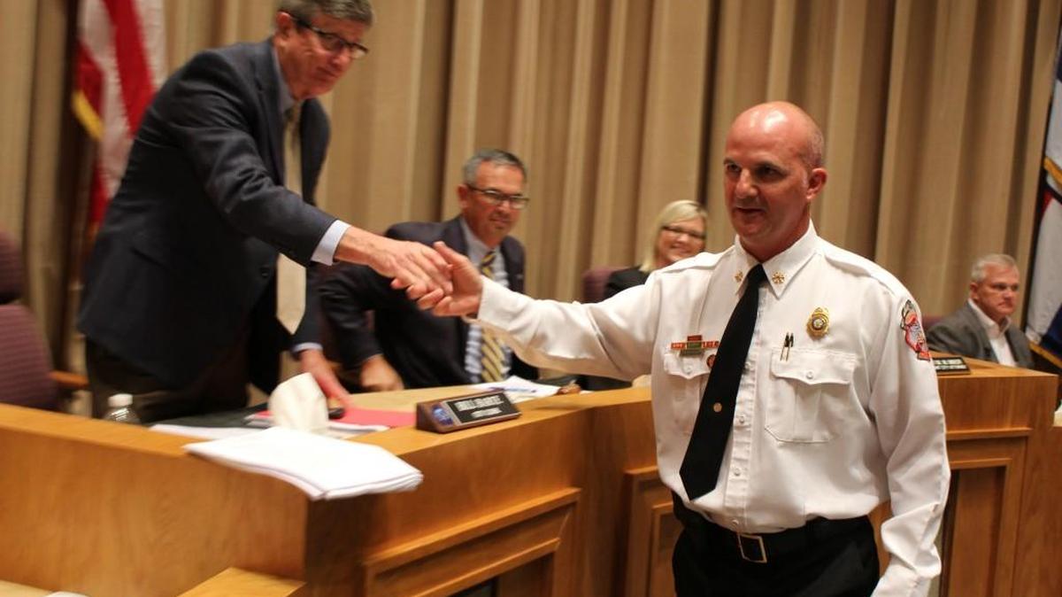 Ross Moulton accepts congratulations from City Clerk Bill Harte after Moulton was named the city’s next fire chief Tuesday.