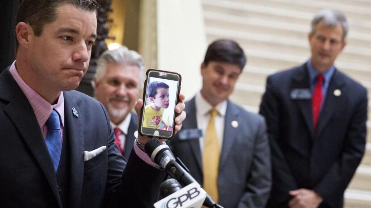 Dale Jackson shows a video of his eight-year-old autistic son Colin saying his first word after being treated with cannabis oil as state lawmakers look on during a press conference at the Capitol in Atlanta, Tuesday, March 28, 2017. Two years after Georgia legalized medical marijuana, lawmakers are opening the popular program to more patients. The House approved a bill Tuesday that would add six new diagnoses to the list of qualifying conditions for medical cannabis oil, including autism, AIDS, Tourette's syndrome, and Alzheimer's disease.