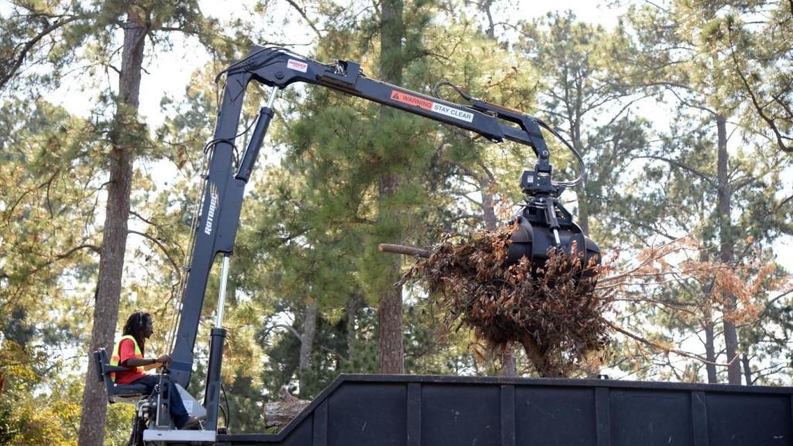 Lee Brown, sitting in the driver's seat of a truck-mounted crane, loads debris from Tropical Storm Irma along Upper River Road in Macon in October.