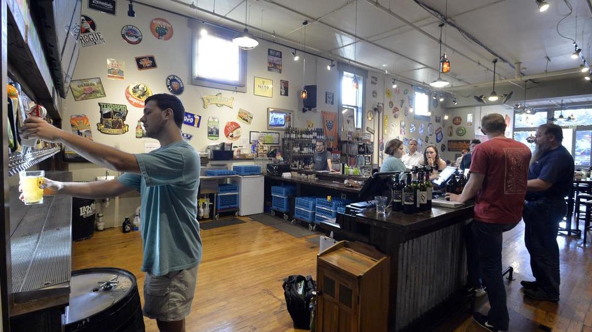 Drew Forrester pours a glass of one of dozens of craft beers on tap at Just Tap’d, Macon's first growler selling location on First Street.
